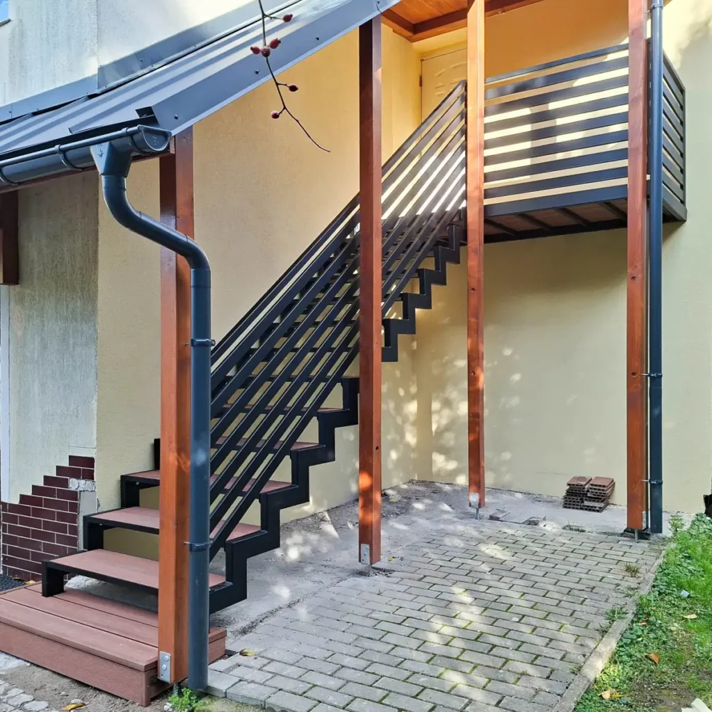 Schody zewnętrzne zadaszone z metalową poręczą i drewnianymi stopniami w Karpaczu.