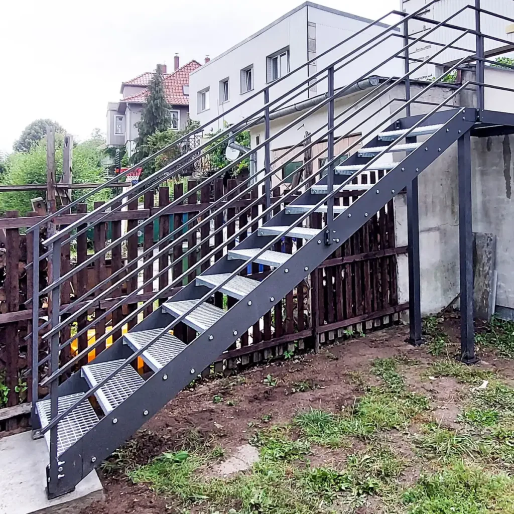 Schody metalowe kratownicowe z metalowymi poręczami.